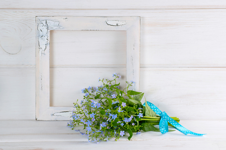 Forget-me-not flowers bouquet and vintage photo frame on white wooden shabby board in provence styleの写真素材