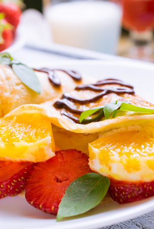 Pancakes with sliced strawberries and chocolate on the shabby wooden boardsの写真素材