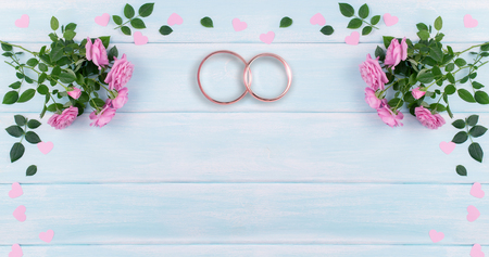 Top view of pink roses and bridal rings for wedding on background of shabby wooden background and place for your textの写真素材