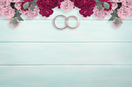 Top view of pink roses and bridal rings for wedding on background of shabby wooden background and place for your textの写真素材