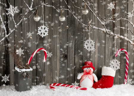 Christmas interior with decorative branches, snowman, Santa boot,  presents and candy canes on wooden planks background. New Year winter composition.の写真素材