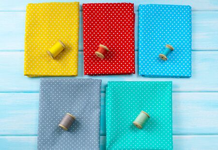 Workplace for seamstress. Top view of set of reel of thread and cloth in polka dot for sewing and needlework on wooden surface.の写真素材