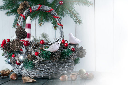 Christmas background with wicker basket, two birds, candle, fir tree, pine and spruce cone, acorns on shabby wooden old table, New Year winter holiday home natural material decor. Empty space for textの写真素材