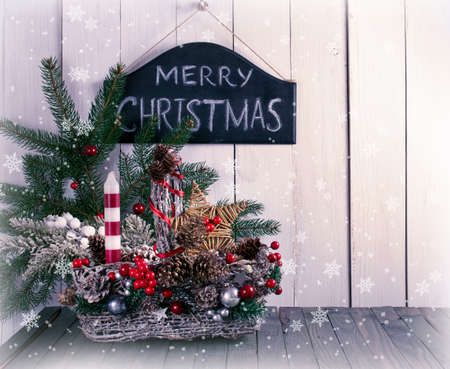 Merry Christmas background with wicker basket, fir tree on shabby wooden old table, blackboard with inscription on white wall, New Year holiday rustic home interior decor.の写真素材