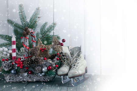 Christmas background with wicker basket, skates for figure ice skating, fir tree on shabby wooden old table, New Year holiday rustic home interior decor.の写真素材