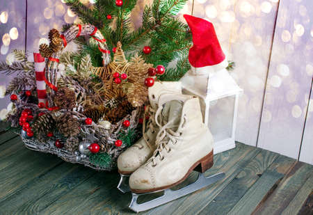 Christmas background with wicker basket, skates for figure ice skating, fir tree on shabby wooden old table, New Year holiday rustic home interior decor.の写真素材