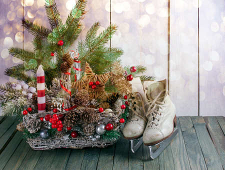 Christmas background with wicker basket, skates for figure ice skating, fir tree on shabby wooden old table, New Year holiday rustic home interior decor.の写真素材