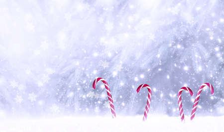 Christmas fabulous card with candy canes lollipops in snowdrift on winter snow background with snowfall and snowflakes. Fantasy new year landscape with snowy fir tree forest, copy space.の写真素材