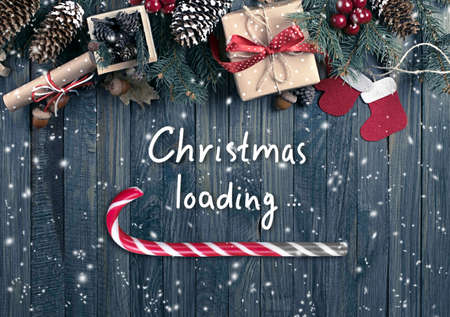 Christmas concept with loading bar in candy cane form, holiday sweet peppermint stick showing progress load on wooden boards background, xmas design with lollipop, gift box on table and inscription.の写真素材
