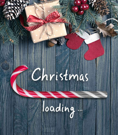 Christmas loading bar in candy cane form, sweet peppermint stick showing progress load on wooden boards background, xmas holiday concept design with lollipop, gift box on table and inscription.の写真素材