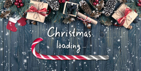 Christmas concept with loading bar in candy cane form, holiday sweet peppermint stick showing progress load on wooden boards background, xmas design with lollipop, gift box on table and inscription.の写真素材