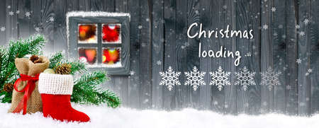 Christmas loading bar in snowflakes form showing progress load on wooden boards background, Santa's boot and bag with gifts, fir tree and cones on house wall background and glowing lights in window.の写真素材
