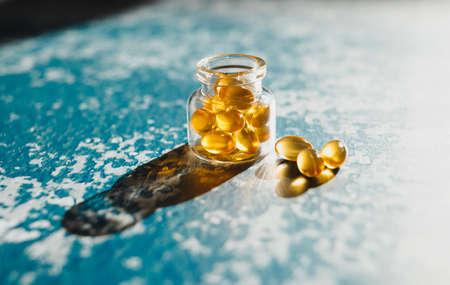 Cod liver capsules lined on decorative blue background.の写真素材