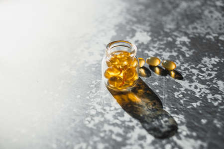 Yellow cod liver capsules lined in a glass bottle on a gray background.の写真素材