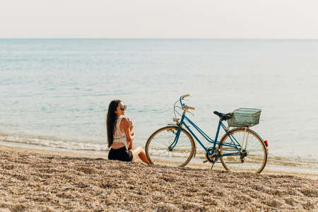 Charming girl in wedding dress standing on stone on sea backgroundの写真素材