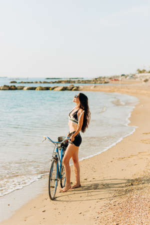 Charming girl in wedding dress standing on stone on sea backgroundの写真素材
