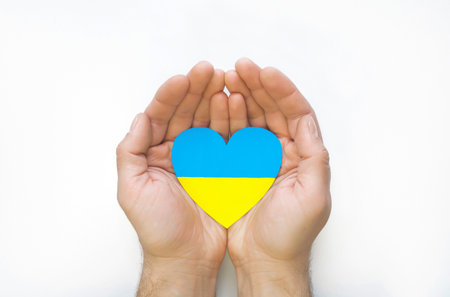 The concept of ending the war in Ukraine. Heart in the colors of the flag of Ukraine in men's handsの写真素材