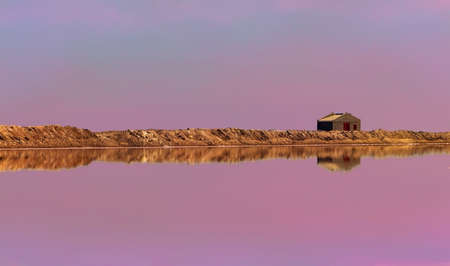 Small stone house and its reflection on a blurry pink backgroundの写真素材