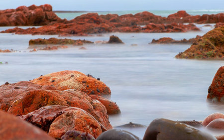 Slow shutter speed photographing water surrounding rock formation in Namibia, Africa at sunset in...