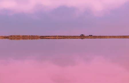 Small stone house and its reflection on a blurry pink backgroundの写真素材