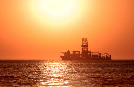 A large vessel on horizon in the atlantic ocean under the bright sun and red sunset.  Sunlight reflection off the waterの写真素材