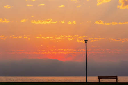 Street lamp and bench in front of the dramatic clouds sky backgroundの写真素材