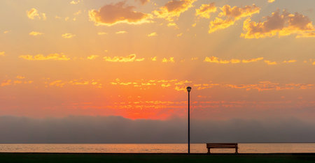 Street lamp and bench in front of the dramatic clouds sky background