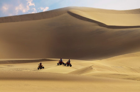 Driving off-road with quad bike or ATV vehicles. Namib sand desert on the background