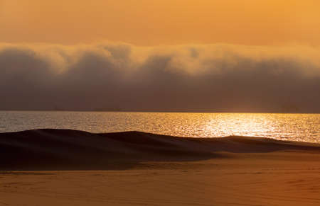 Heavy dramatic clouds and bright sky over the Atlantic Ocean. Beautiful african desert sunsetの写真素材
