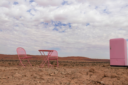 Two pink chairs, a table and a refrigerator stand in the Namib desert against the backdrop of a...
