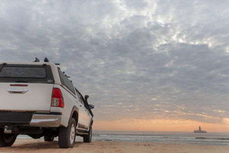 White off-road car stands on the shores of the atlantic ocean at a bright dramatic sunset. Namibiaの写真素材