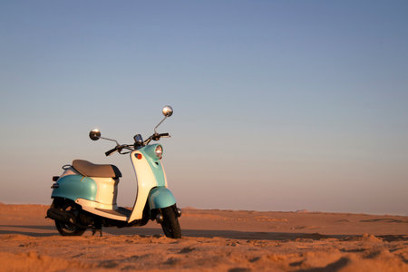 Retro blue scooter at sunset in the golden sand of the Namib Desertの写真素材