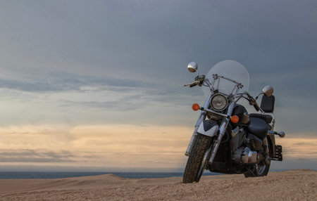 A motorcycle stands still beneath a vibrant sunset, symbolizing freedom, adventure, and the thrill of exploring new roads ahead.の写真素材