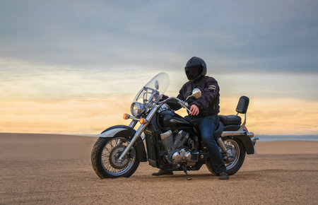 Man on motorcycle in desert during sunset with dramatic clouds â concept of freedom, travel, solitude, adventure, and outdoor lifestyle in wild open landscapesの写真素材