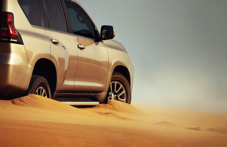 Detailed view of a car stuck in thick desert sand, emphasizing power, resistance, and the harsh...
