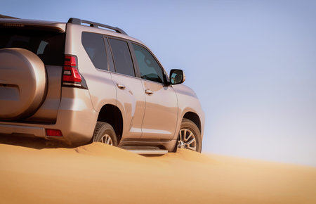 Detailed view of a car stuck in thick desert sand, emphasizing power, resistance, and the harsh...