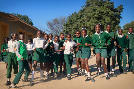 Authentic image of happy African kids in school attire, enjoying time together outside. A candid, heartwarming moment full of energy, unity, and youthful optimism.の写真素材