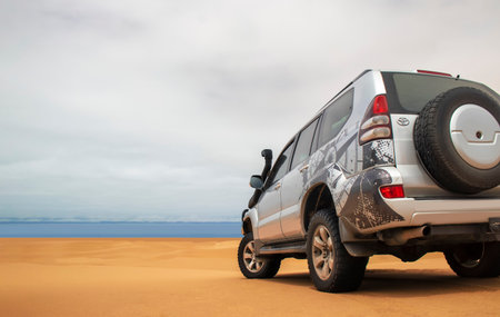 A powerful gray 4x4 SUV stands alone in the vast sandy terrain of the Namib Desert, ready for off-road travel, exploration, and endurance across one of Africaâs wildest landscapes.の写真素材