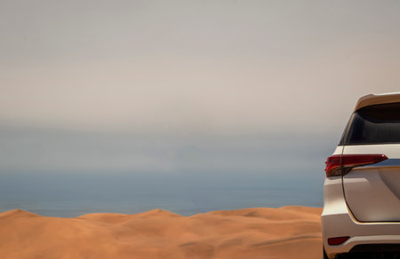 In the heart of the Namib Desert, a white car crosses the sunlit dunes, embodying adventure, strength, and the spirit of travel in Southern Africa.の写真素材