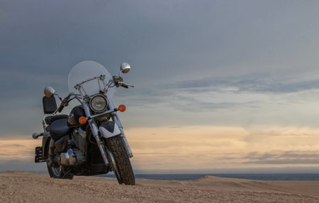 A dirt bike parked alone in the open desert, framed by stormy clouds. Perfect for themes of...