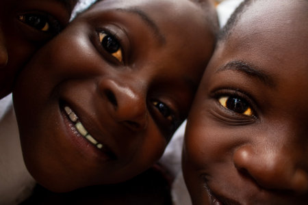 Premium close-up of happy African schoolchildren in uniforms, laughing together outdoors. A powerful and uplifting image capturing real joy, childhood, and cultural connection.の写真素材