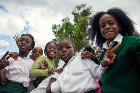Real photo of happy black African kids in school uniforms, smiling and enjoying a break. A positive image of youth, education, diversity, and community spirit.の写真素材