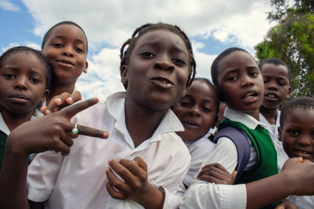 Real photo of happy black African kids in school uniforms, smiling and enjoying a break. A positive image of youth, education, diversity, and community spirit.の写真素材