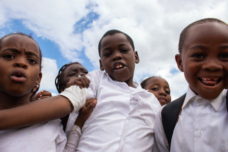 Real photo of happy black African kids in school uniforms, smiling and enjoying a break. A positive image of youth, education, diversity, and community spirit.の写真素材