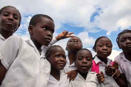 Real photo of happy black African kids in school uniforms, smiling and enjoying a break. A positive image of youth, education, diversity, and community spirit.の写真素材