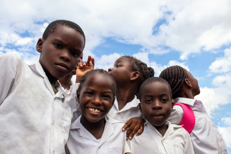 Real photo of happy black African kids in school uniforms, smiling and enjoying a break. A positive image of youth, education, diversity, and community spirit.の写真素材