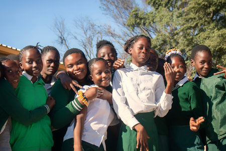 Real photo of happy black African kids in school uniforms, smiling and enjoying a break. A positive image of youth, education, diversity, and community spirit.の写真素材