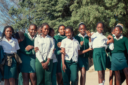 Real photo of happy black African kids in school uniforms, smiling and enjoying a break. A positive image of youth, education, diversity, and community spirit.の写真素材