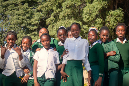 Real photo of happy black African kids in school uniforms, smiling and enjoying a break. A positive image of youth, education, diversity, and community spirit.の写真素材