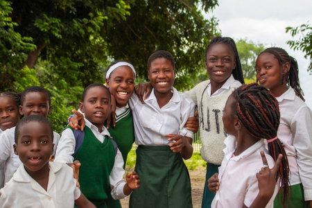 Real photo of happy black African kids in school uniforms, smiling and enjoying a break. A positive image of youth, education, diversity, and community spirit.の写真素材